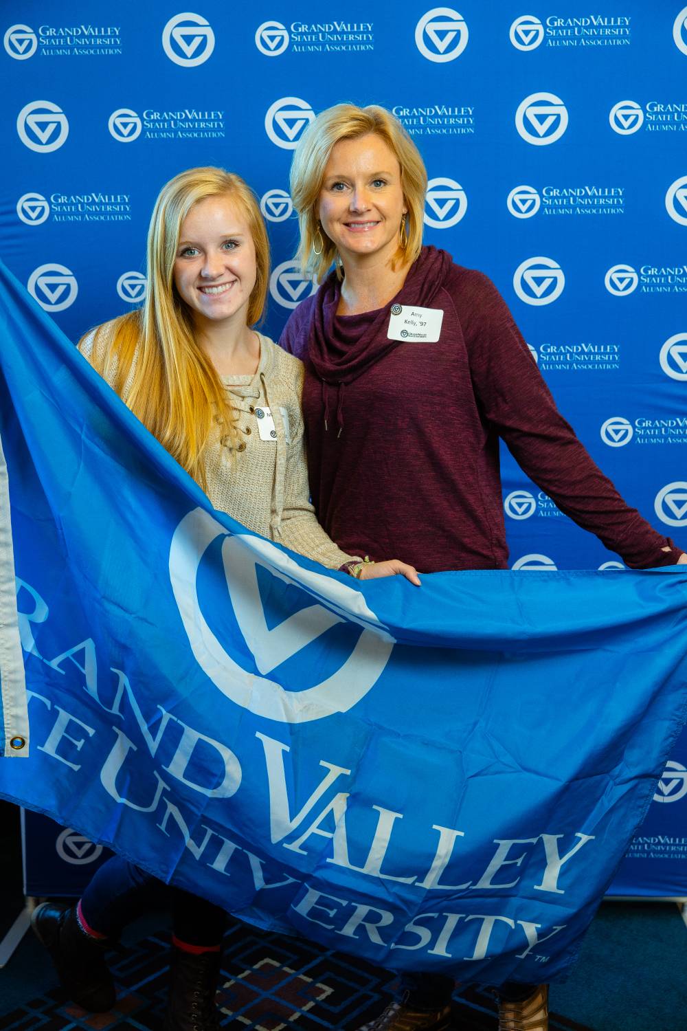 Two alumni pose for a photo with the GV flag